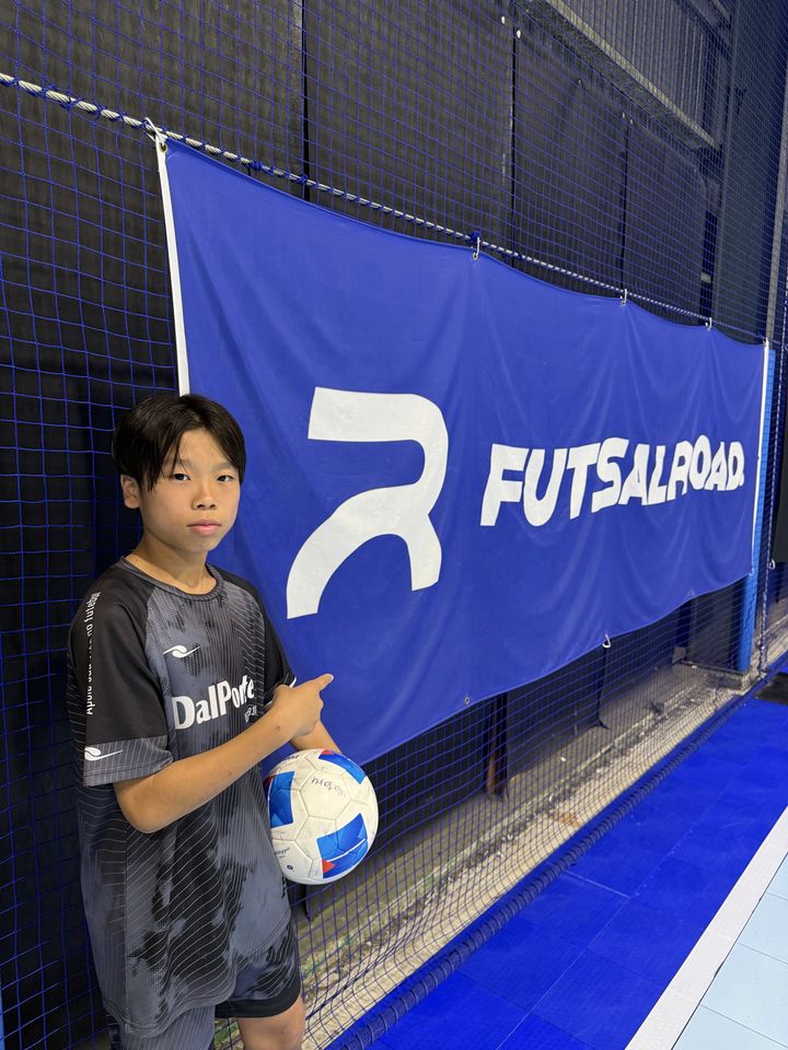 フットサルロードのバナーを指さすWataru